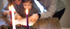 parent and child reading devotion in front of advent candle