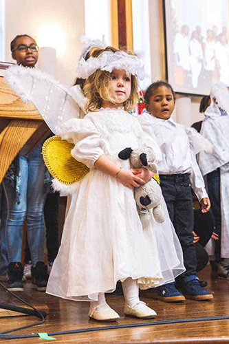 Little girl dressed as angel with other children behind her
