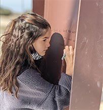 girl writing on a construction beam