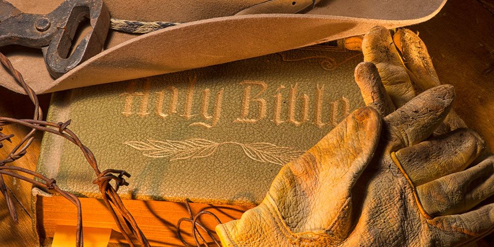 Bible with cowboy hat and gloves on it