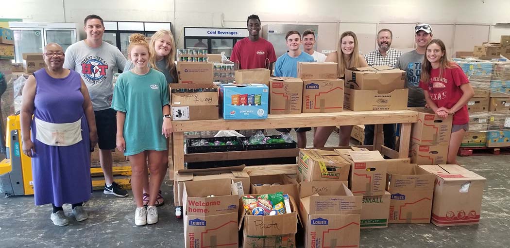 11 volunteers with boxes of food at a food pantry