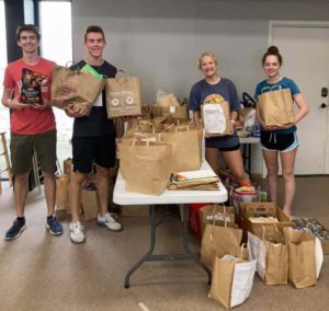 Four teenagers with bags of groceries to donate