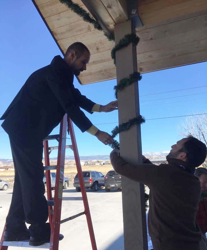 Pastor Matt Frey on ladder hanging Christmas decorations