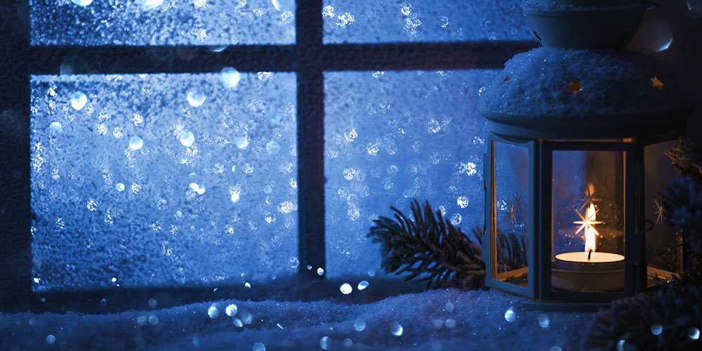 candle in window, looking out window to a snowy landscape
