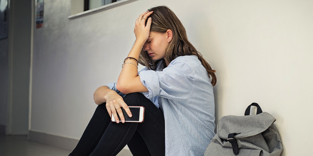 upset teen girl sitting by wall