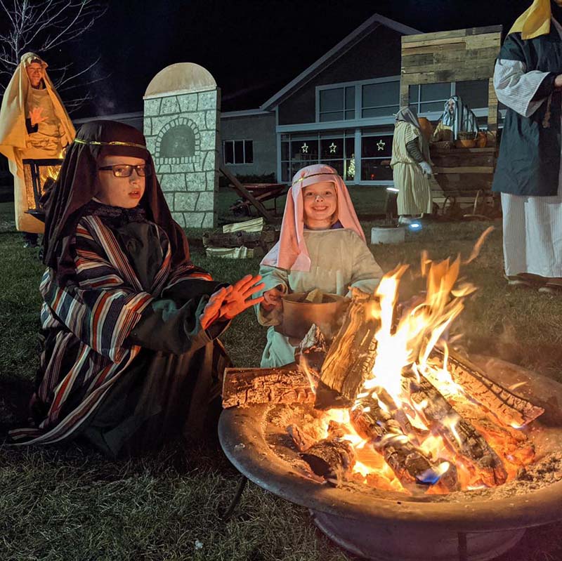 Two children warming themselves by a bonfire at the living nativity at St. Matthew, Oconomowoc, Wis.