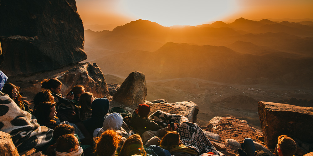 adults watching sunset on mountain