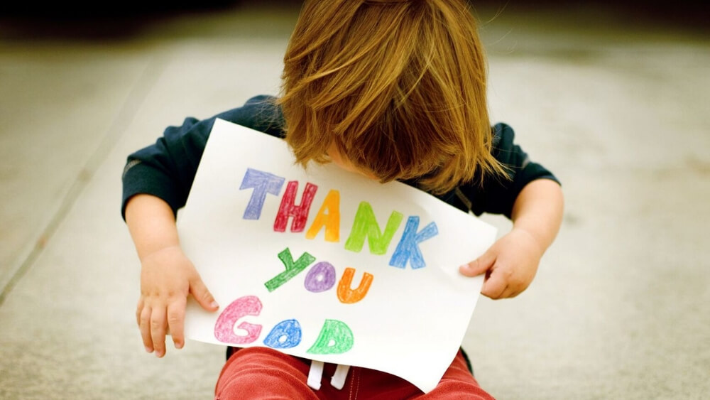 kid holding a thank you God colored sign