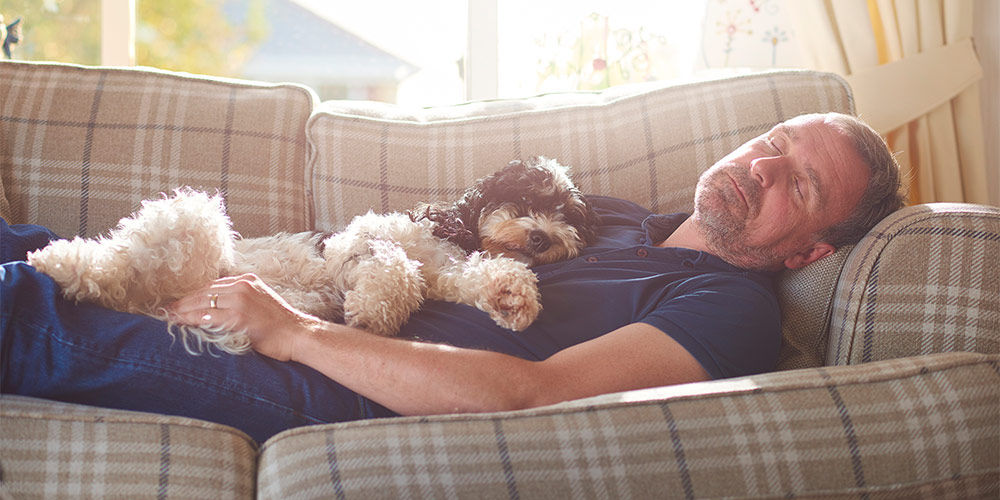 man sleeping on couch with dog