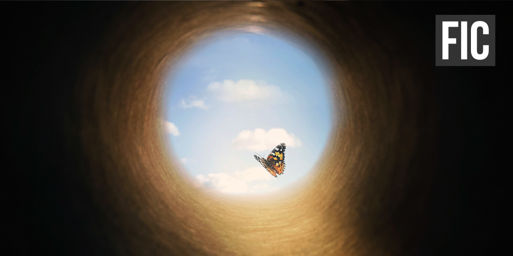 A butterfly is flying out of a dark hole into a bright blue sky