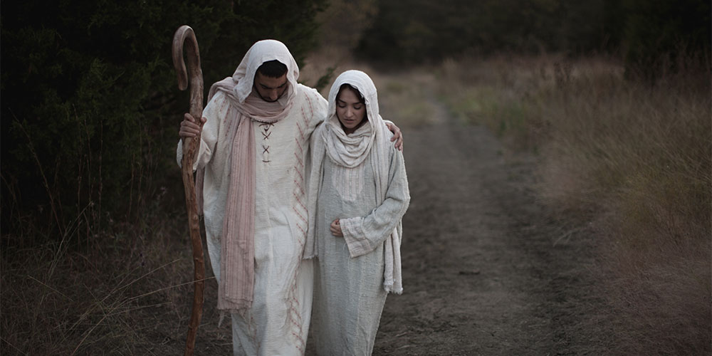 Joseph and pregnant Mary walking along path