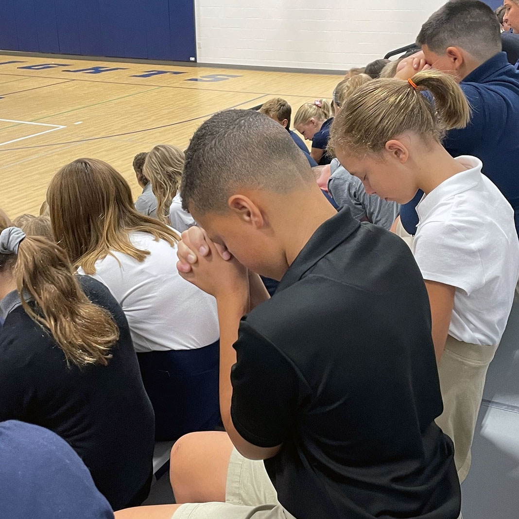 Children saying prayer in gym