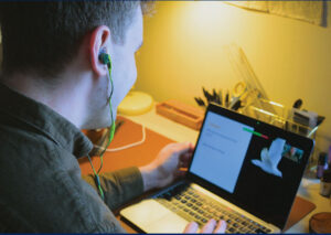 Man listening to headphones plugged into computer