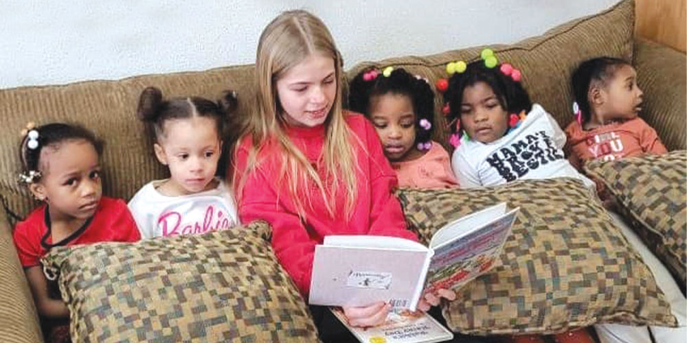 girl reading to toddlers