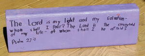purple piece of wood with a bible verse written on it