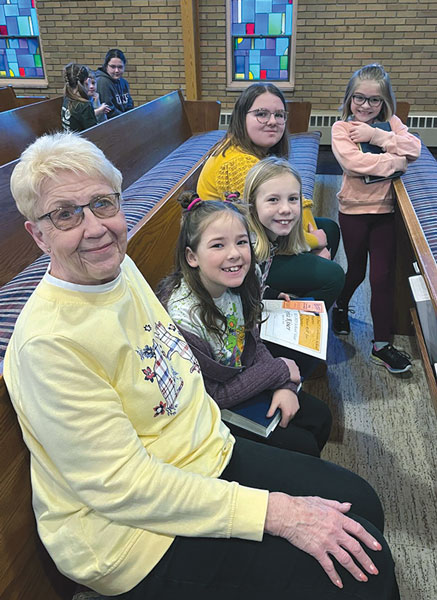 older lady in pew with 4 girls