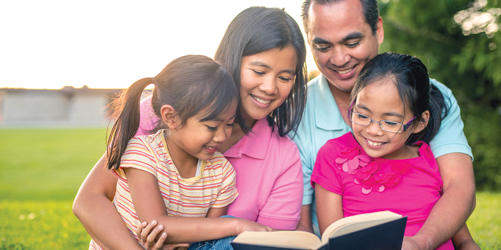 Asian family reading book outside