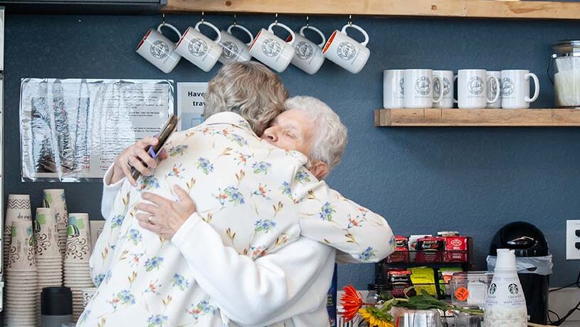 Two females hugging in the coffee area of Carbon Valley Lutheran Church