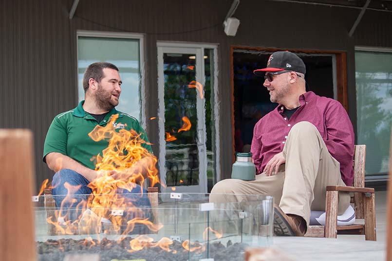 Two male members at Carbon Valley Lutheran gathering around the church's fire pit for fellowship