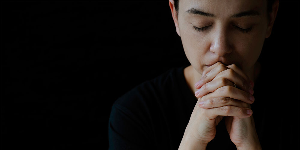 black background with woman praying and eyes closed