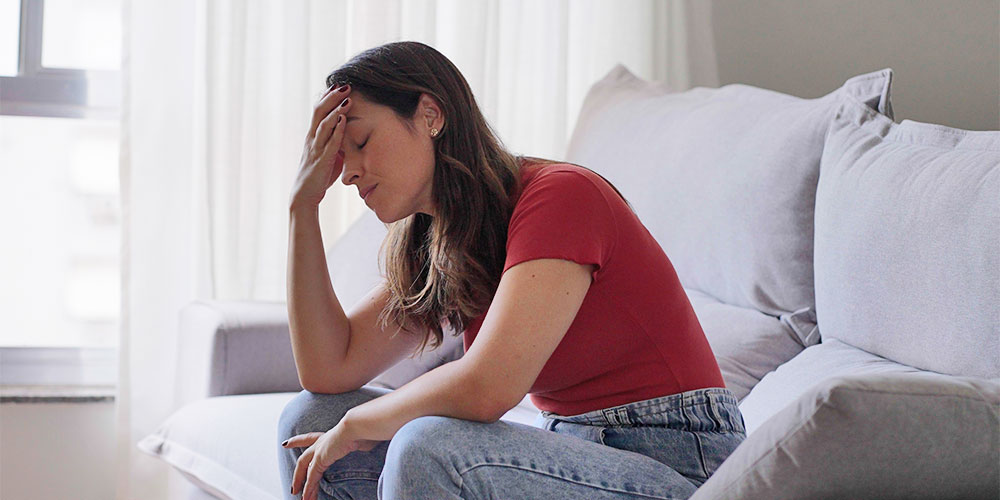 Woman sitting on couch looking defeated. Freepik image