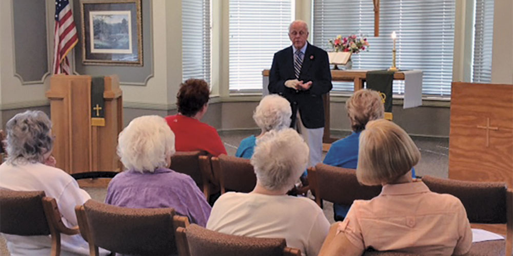 older gentleman talking to woman sitting in chairs church