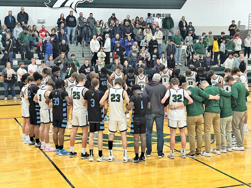 group of boy basketball players in prayer circle before game starts