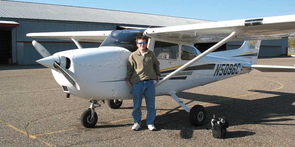 young man standing by airplane