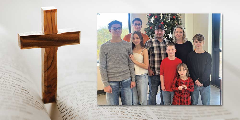 bible and cross up close with family in front of christmas tree