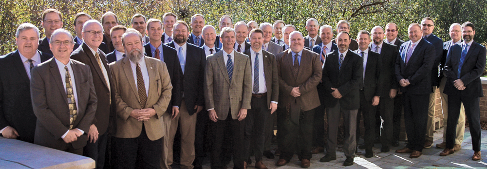 a bunch of men in suits posing for a photo working together