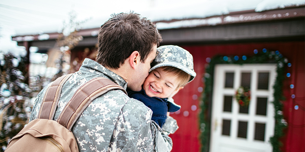 military dad home for christmas hugging and kissing son