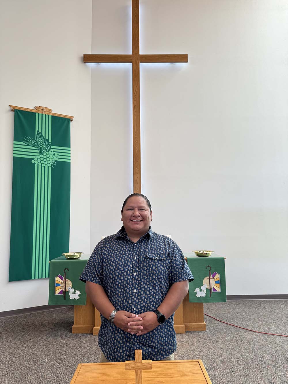 Aaron Newman in the front of church with altar and cross behind him