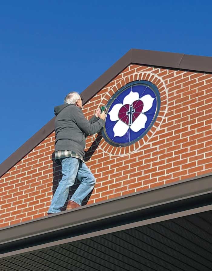 man working on luther seal on front of building