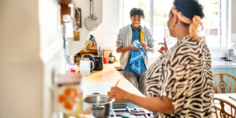 woman cooking talking to teen son who is drying dishes blue towel