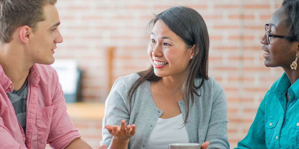 three people talking outside 2 men and a woman white, asian, black