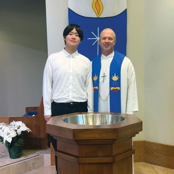 pastor and asian man at baptism font