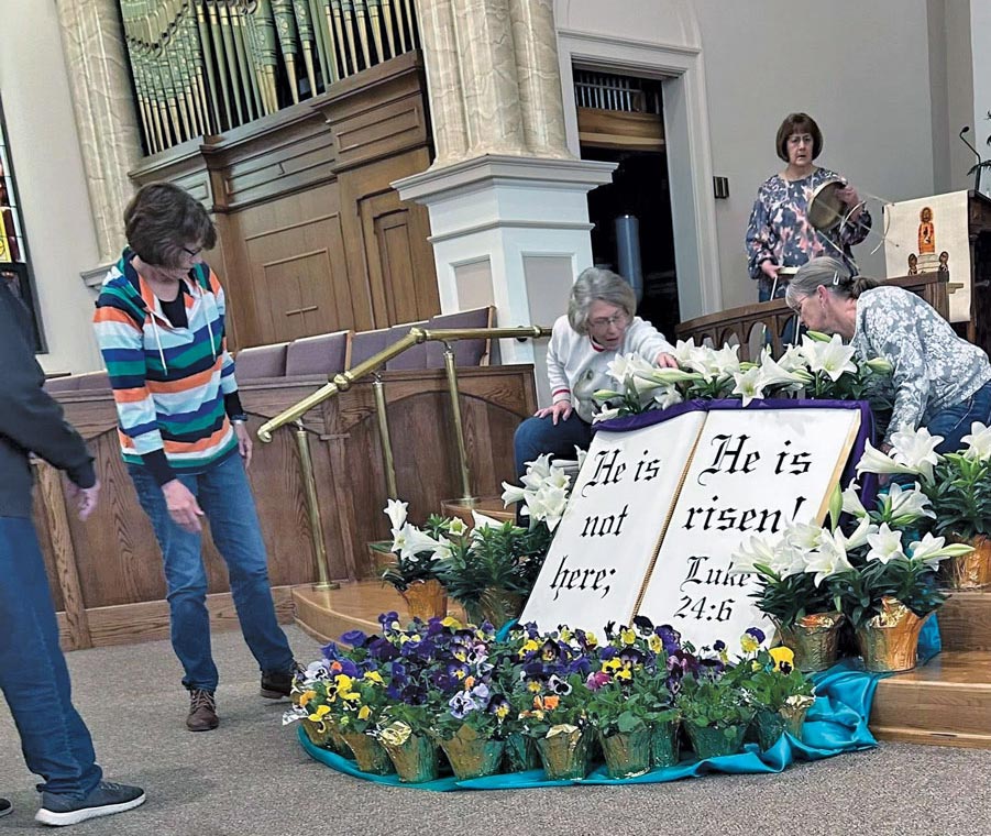 Decorating the interior of the altar for Easter at a church. Flowers and He is risen sign