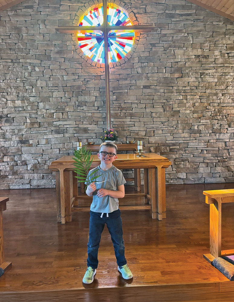 Young boy holding a palm in the front of church on palm sunday