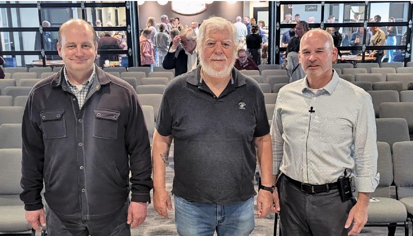 photo of 3 men in black and grey in front of church