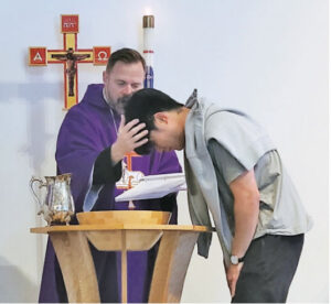 boy being baptized by pastor wearing purple