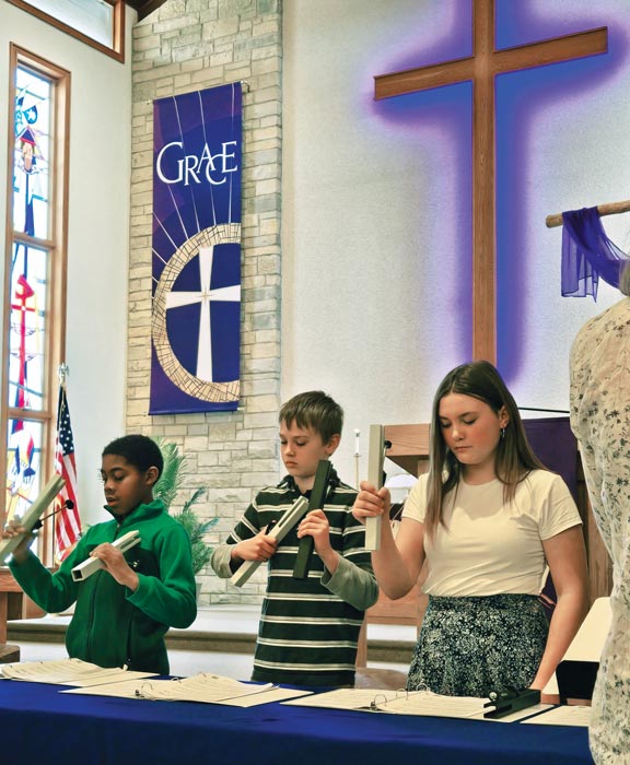 children playing bells in front of church. Purple