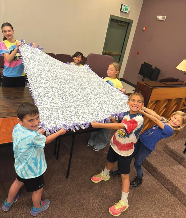 young kids holding a tie blanket