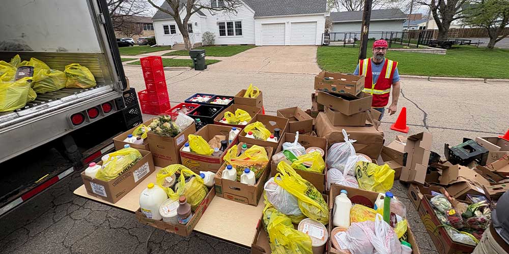man standing in front of boxes of groceries donated. yellow bags