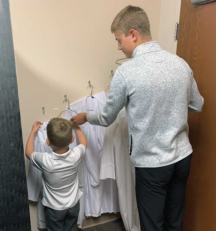 teen helping young boy with robe
