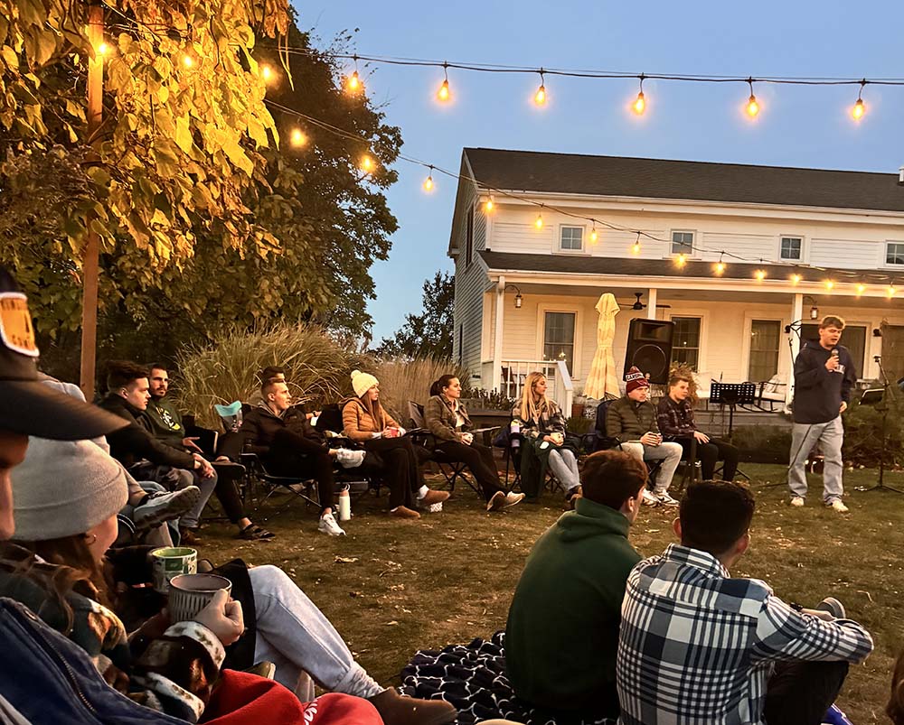 Young people worshiping in a backyard, sitting in camping chairs
