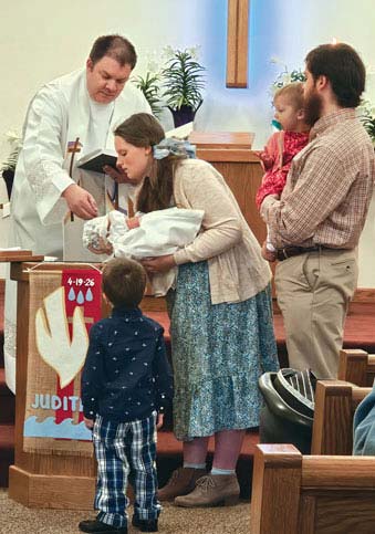 baptism of baby dad holding daughter son watching baptism plaid pants