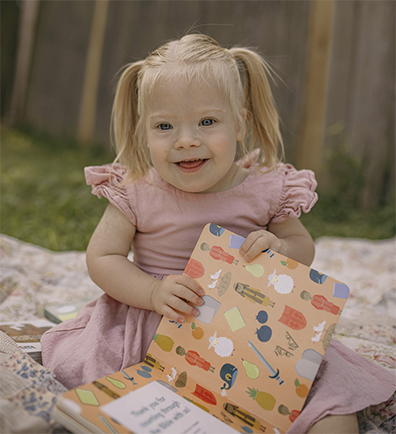 Evangeline Fury sitting on blanket outside with book