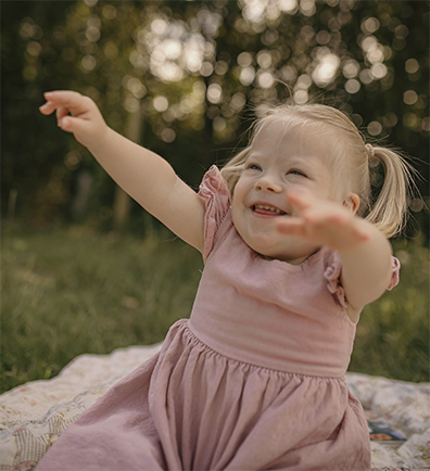 Evangeline Fury sitting on blanket outside reaching up