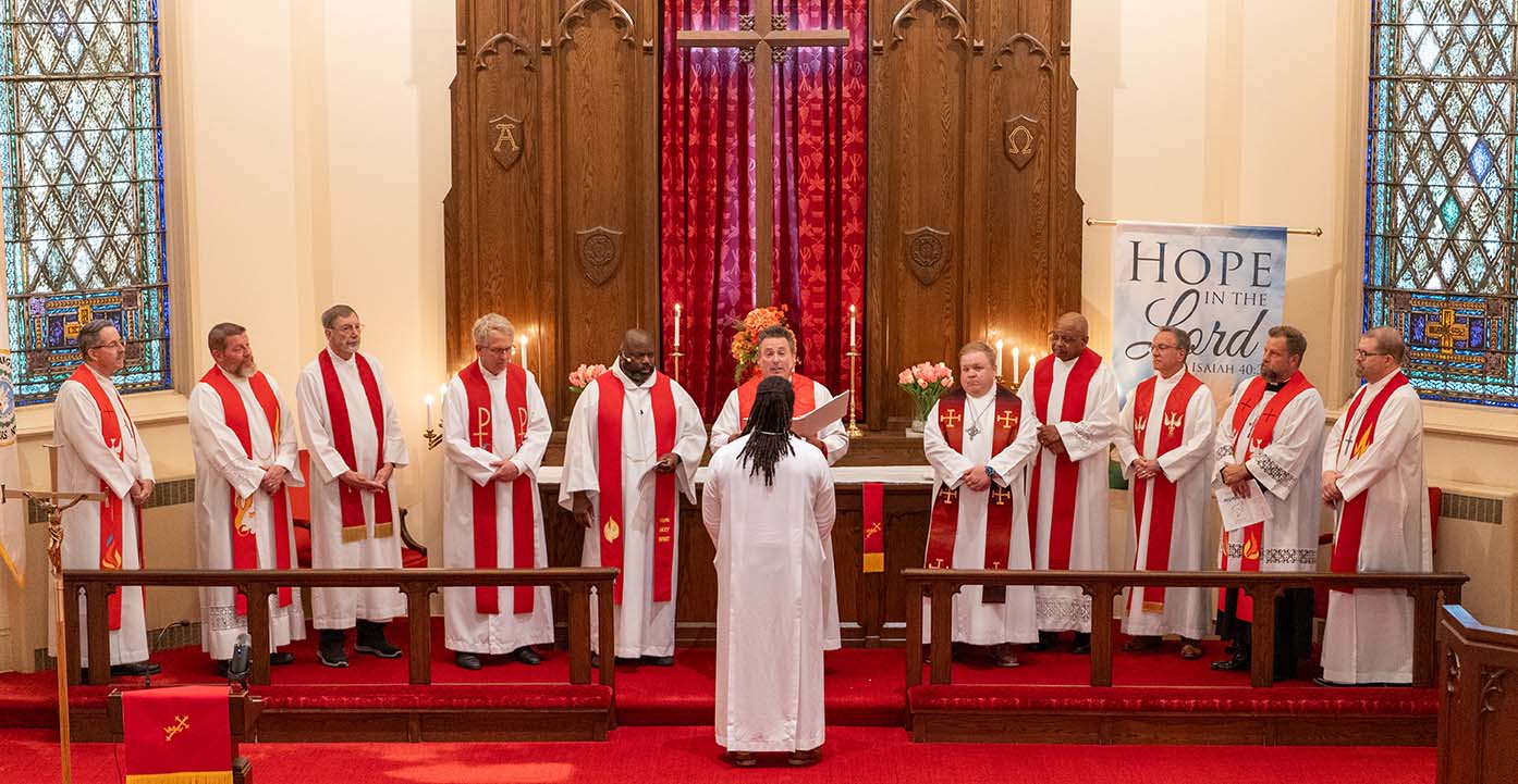 Eleven pastors bestowing blessings from God's Word on Keri Jackson during his ordination service