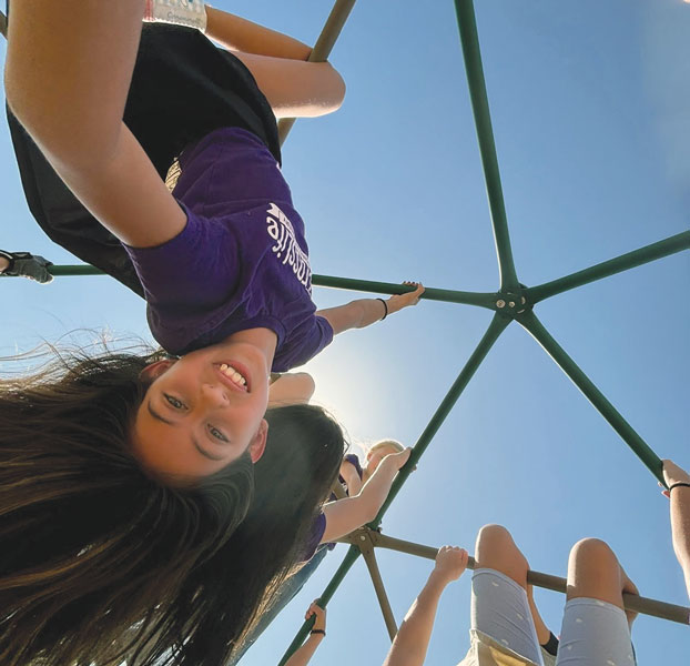 girl hanging from a jungle gym
